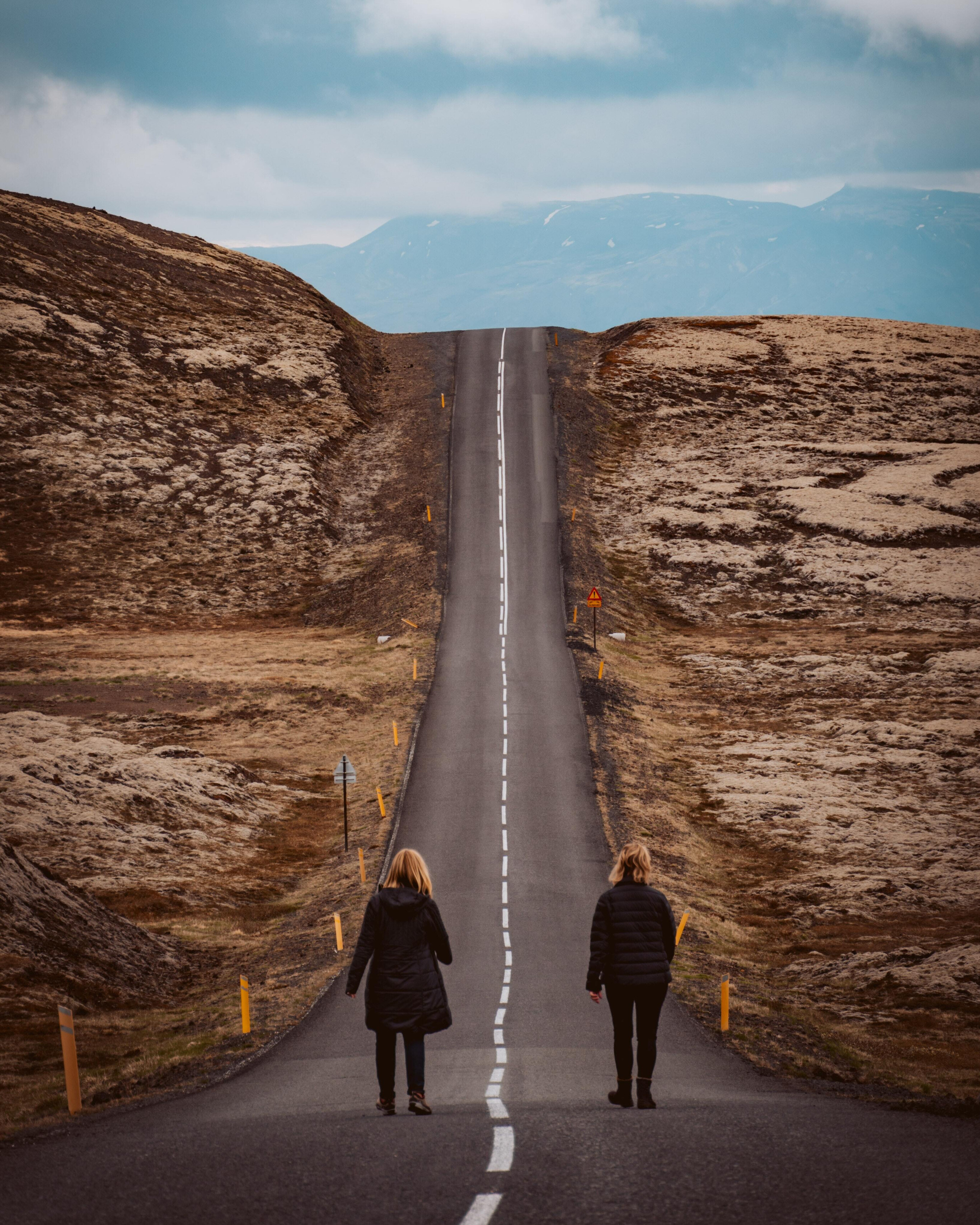 two people walking down a long road