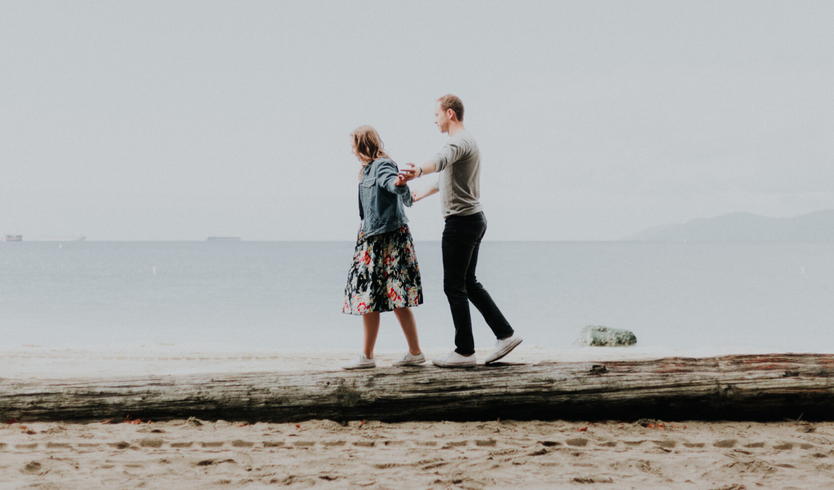 A couple balancing on a fallen tree.