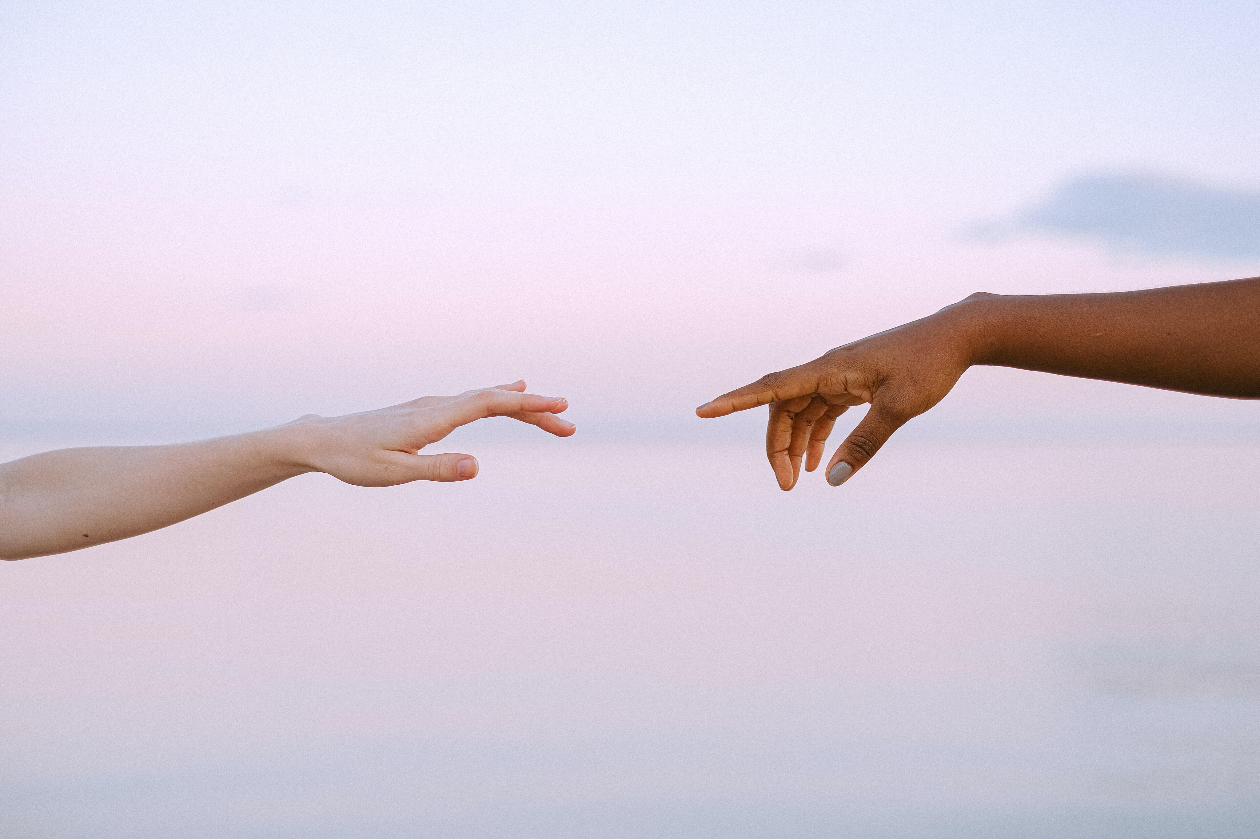 two hands reaching for each other by water